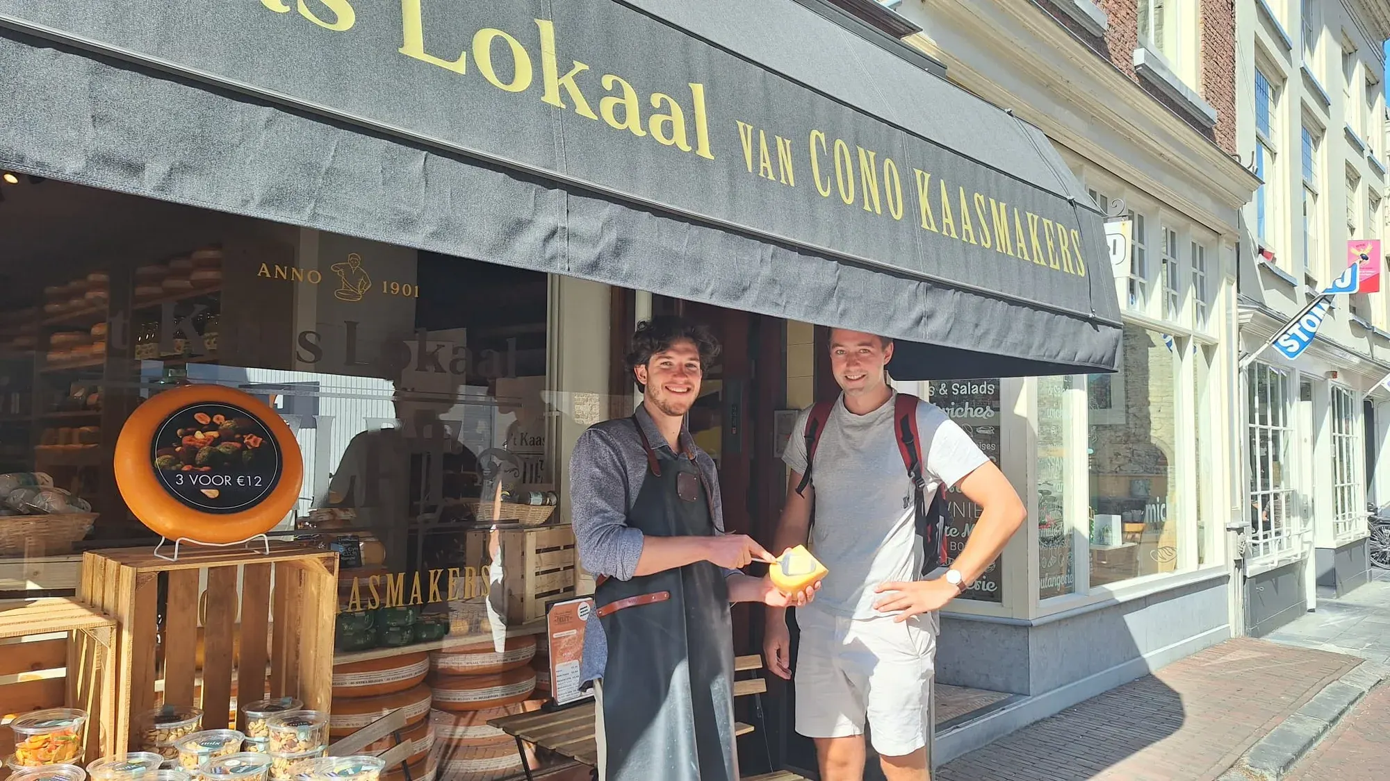 Een gids en een gast proeven kaas voor Kaaslokaal, een kaaswinkel in Delft