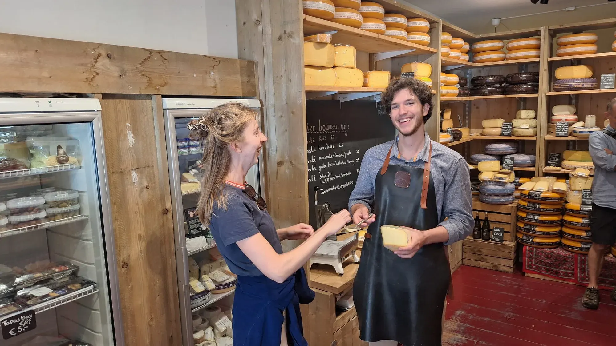 Medewerkers van Kaaslokaal geven gasten Nederlandse kaas te proeven aan de toonbank tijdens de privé food tour in Delft