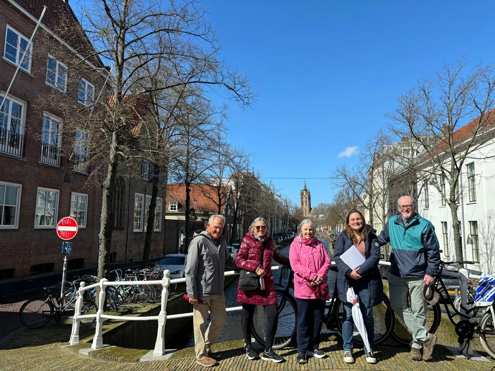 A small private tour group with their guide on a bridge overlooking a Delft canal, on The Delft Challenge route
