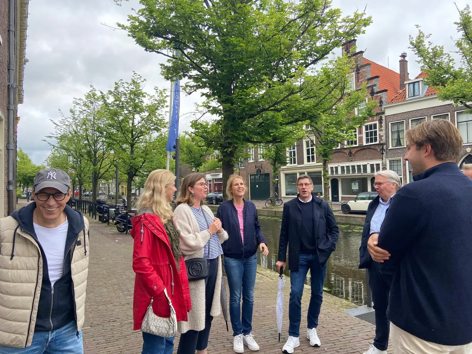 A guide and private tour group talking beside a canal in the old centre of Delft