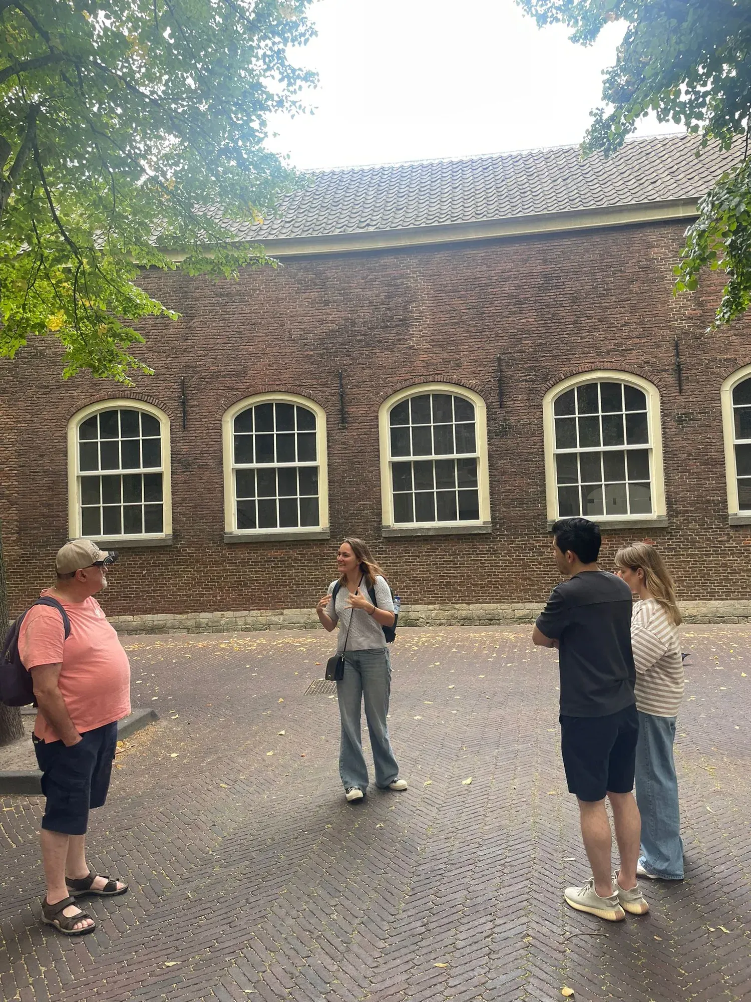 A guide speaking to a small team in the Prinsenhof courtyard, Delft