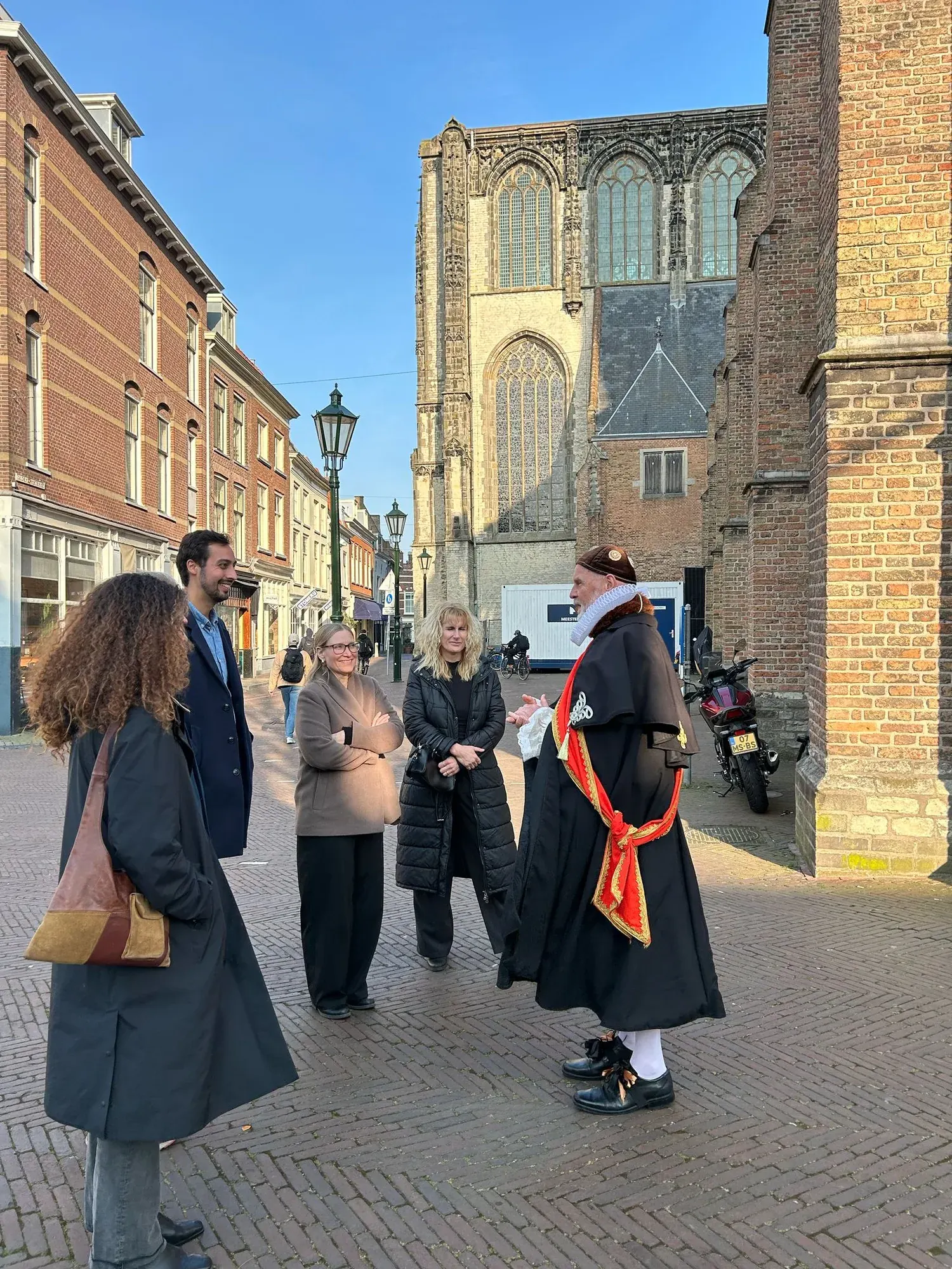 A team building group talking with a costumed guide dressed as William of Orange, outside the Oude Kerk in Delft