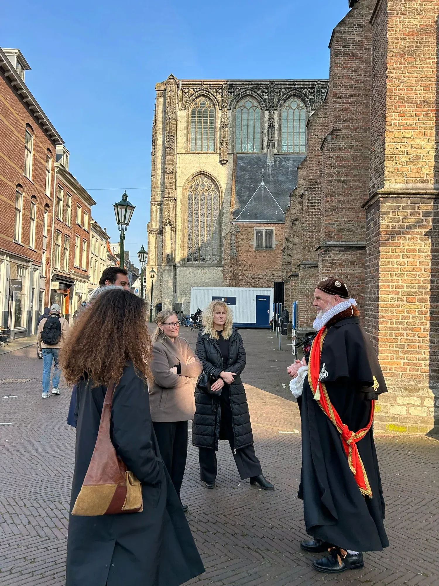A guide in historical costume with a group at the Oude Kerk in Delft