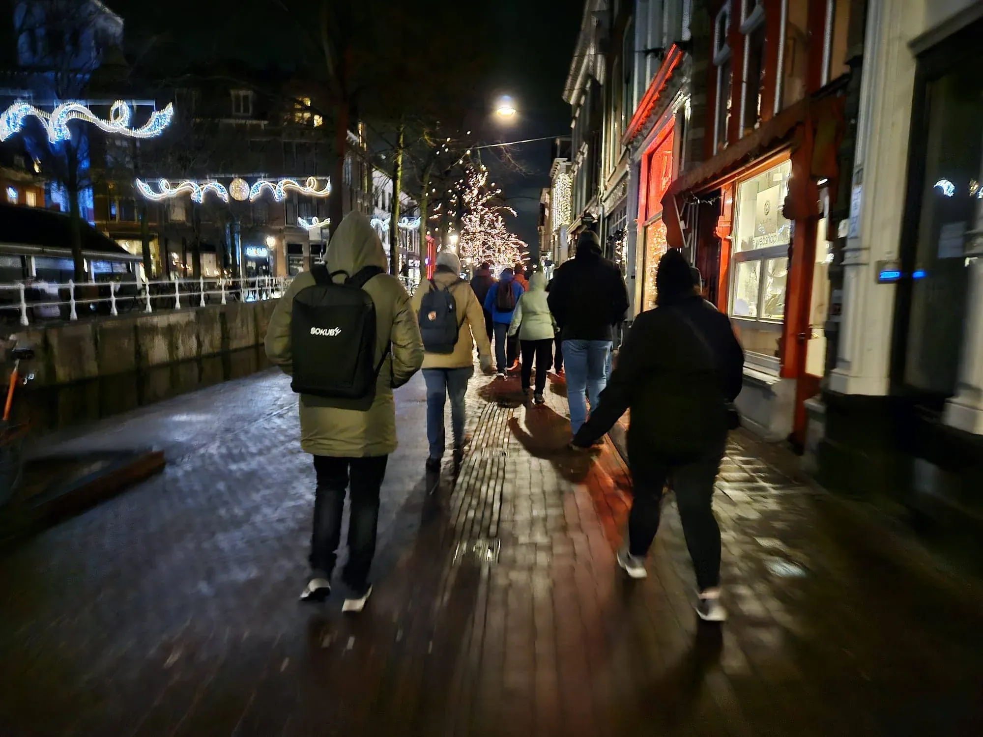 A group walking through the illuminated old town of Delft in the evening