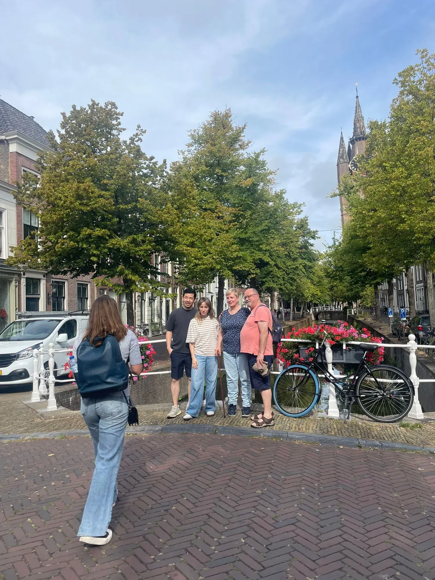 A private tour group on a Delft canal bridge with the Oude Kerk tower behind, on the Highlights of Delft walking tour