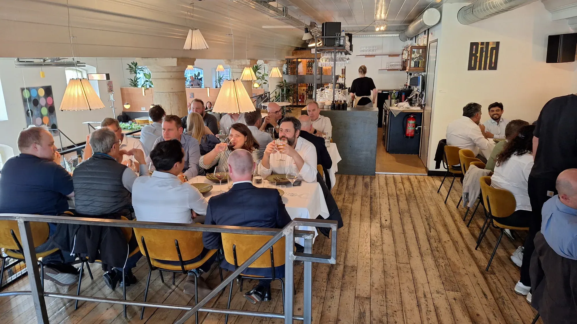 A large group of colleagues at long tables during a walking dinner in Delft