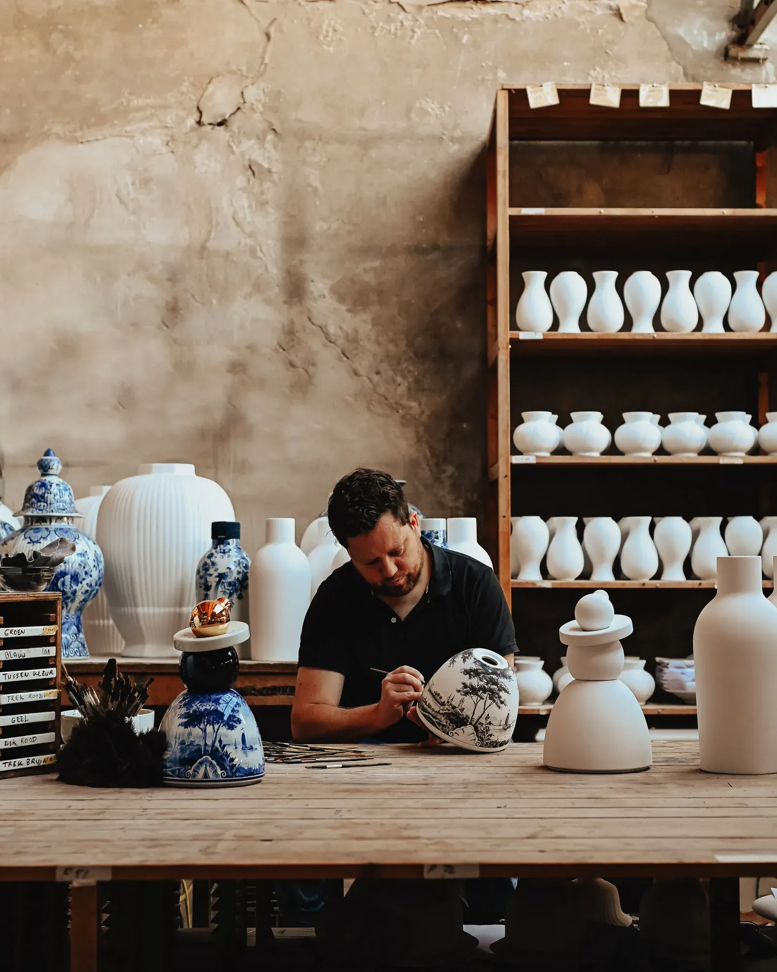 An artisan hand-painting Delft Blue pottery in the Royal Delft workshop, seen on the Royal Delft factory tour