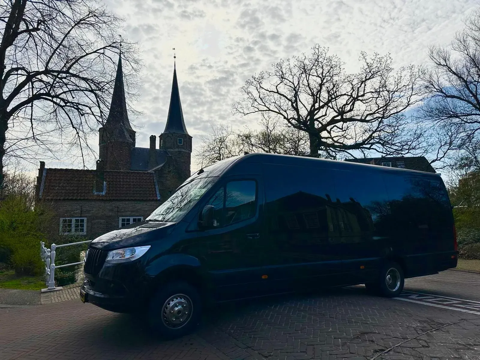Black minibus of a small-group shore excursion parked in front of the Oostpoort city gate in Delft