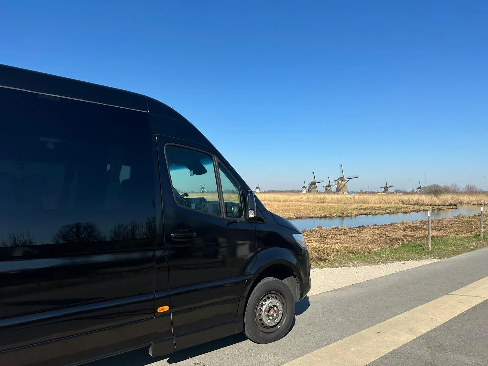The excursion minibus at Kinderdijk with the windmills behind it